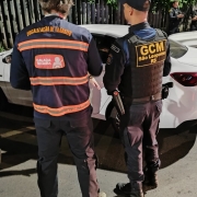 Policial da guarda municipal e do detranrs em abordagem de veículo durante blitz, ambos de costas