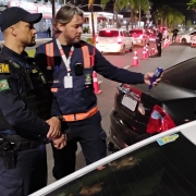 Agente da Balada Segura do DetranRS segura o etilômetro para um condutor e guarda municipal acompanha a ação